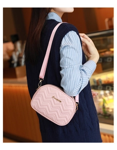 Vue détaillée du sac matelassé rose avec large bandoulière tissée et logo doré