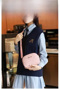 Sac bandoulière rose surpiqué en V avec bandoulière réglable porté par un mannequin