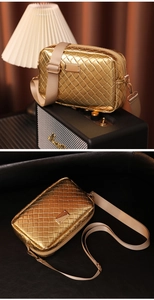 Detail der goldenen gewebten Kameratasche mit breitem Canvas-Gurt und Metall-Finish