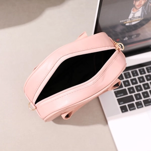Pink quilted crossbody bag with gold zipper showing interior compartment on desk