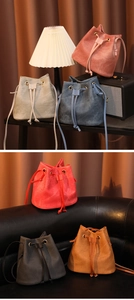 Six sacs seaux en daim de différentes couleurs disposés sur un canapé en cuir noir