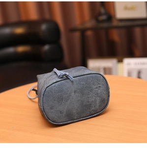 Détail du sac seau en denim bleu gris avec cordon de serrage sur une table en bois