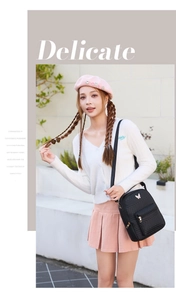 Black quilted crossbody bag with butterfly metal charm shown in a chic outdoor setting