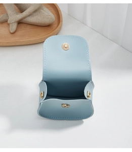 Close-up of light blue mini bag featuring golden magnetic snap and metal D-ring buckle