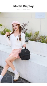 Outdoor shot of a black mini backpack with V-shaped quilting and golden butterfly detail
