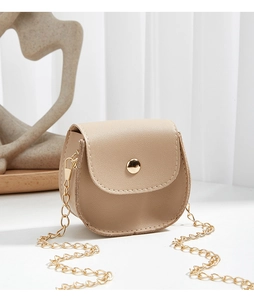 Detail of minimalist beige mini crossbody bag with gold chain strap and textured leather