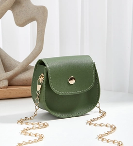 Close-up of mini dark green saddle bag with lychee texture and gold chain strap