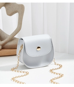 Detail of light blue mini crossbody bag with golden chain and round snap closure