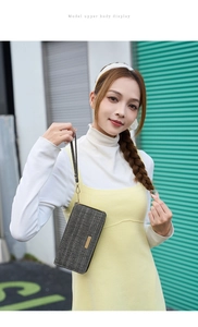 Detail of dark grey herringbone clutch with golden metal zipper and wrist strap
