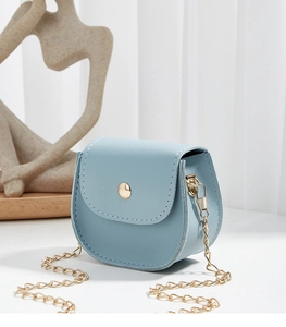 Close-up of light blue mini saddle bag with gold chain strap and white stitching
