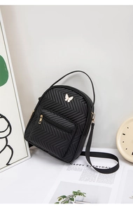 Detail of black quilted mini backpack with golden butterfly hardware and top handle