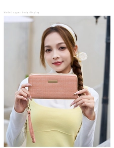 Detail of pink-orange herringbone textured long wallet with gold bar and wrist strap