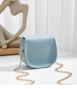 Detailed side view of mini light blue leather saddle bag with refined gold chain strap