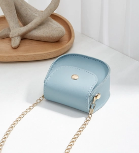 Detail of light blue mini saddle bag with golden metal chain strap and round buckle