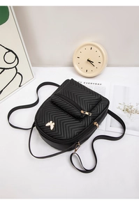 Detail of black quilted leather backpack featuring a golden butterfly metallic buckle