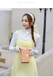 Orange long wallet with woven texture and gold plate held by model in outdoor setting