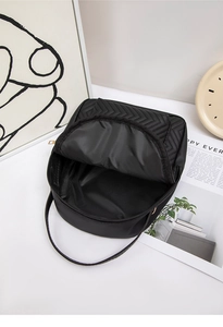Detailed interior of black quilted mini backpack with V-pattern and gold zipper closure