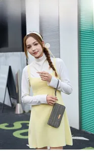Gray woven fabric clutch bag with gold logo plate held by model in city street