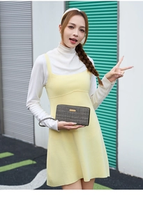 Outdoor street style view of a long grey tweed clutch bag with gold plaque and wrist strap