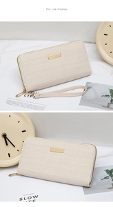 Detailed view of beige long wallet with herringbone texture and gold metal plaque display