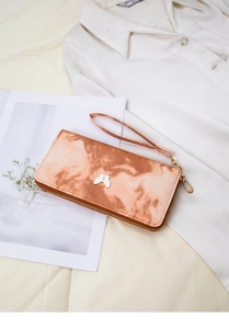 Detail of zip-around wallet with marble pattern, butterfly charm and wrist strap
