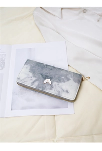 Detail of grey marble pattern wallet with butterfly ornament and gold zipper closure
