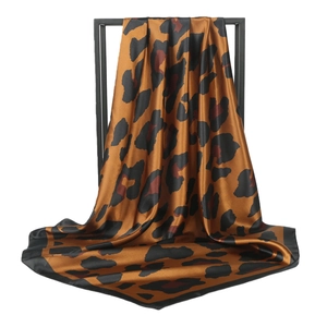 Satin leopard print square scarf in caramel brown with black border on display stand