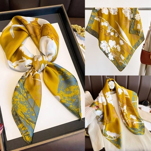 Detail of mustard yellow silk scarf with lily of the valley floral patterns and texture