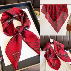 Detail of red plaid silk-like square scarf showing smooth texture and classic tartan pattern