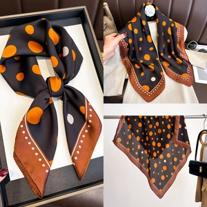 Detailed view of polka dot silk scarf featuring orange and white patterns on black base