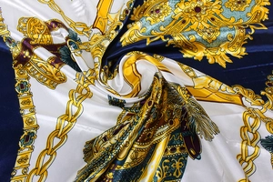 Gros plan d'un foulard en soie à imprimé baroque montrant des chaînes dorées et lisse