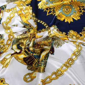 Détail d'un foulard en satin de soie avec des chaînes dorées et des motifs de blasons royaux
