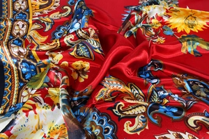 Detailed view of red paisley satin scarf fabric with sunflower patterns and silky gloss