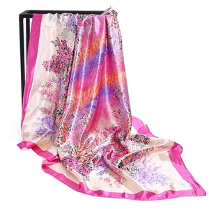 Detail of gradient satin floral scarf with smooth silk texture hanging on a display rack