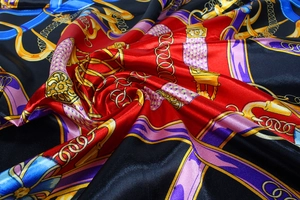 Close-up of luxury silk satin square scarf with chain prints and golden harness patterns