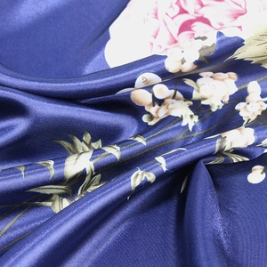 Detail of navy blue silk scarf with pink floral patterns and smooth satin texture