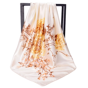 Elegant satin floral square scarf in beige and yellow draped on a black display frame