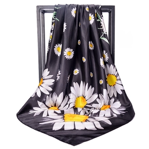 Detail of black silk satin square scarf featuring white daisy prints on a metal frame
