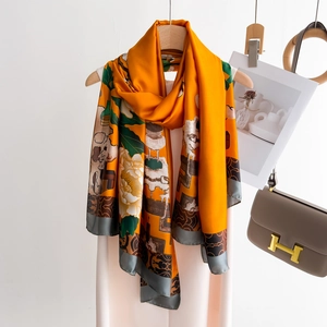 Detailed view of glossy orange silk scarf with elegant white floral patterns