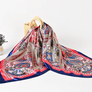 Navy blue paisley silk scarf tied to a straw bag in elegant resort style view