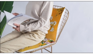 Detailed view of yellow floral cushion on a gold chair in a cozy reading setting