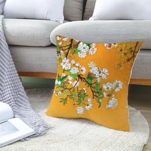 Square floral throw pillow in orange with white flowers on a white plush carpet