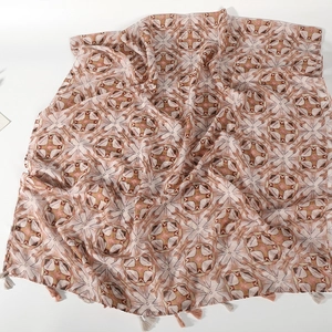 Vue détaillée d'une écharpe en gaze de Bali légère avec motifs floraux et pompons doux