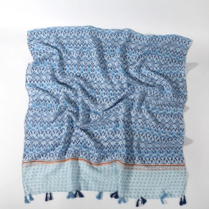 Detail of blue and white geometric print scarf with navy tassels and orange accent