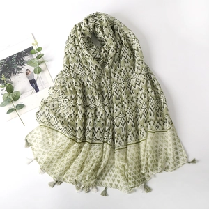 Detail of green printed scarf featuring geometric waves, heart patterns and fine tassels