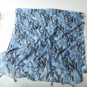 Detail of blue botanical print scarf with delicate fringe trim on lightweight fabric