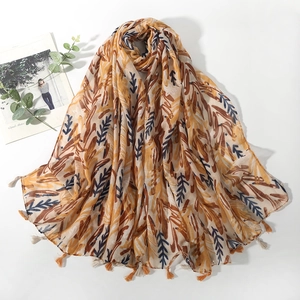 Detail of floral print shawl with orange leaves and soft fringed edges and linen texture