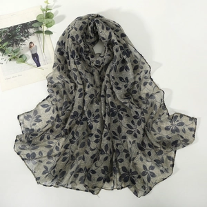 Écharpe gris clair à motif de feuilles en voile fin présentée dans un plat élégant