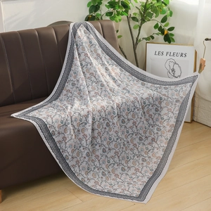 Detail of floral pattern on breathable voile square scarf displayed on a sofa