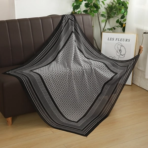 Detail of floral geometric pattern on black and white voile scarf draped on leather sofa